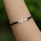 Bracelet noir avec pendentif en forme de croix argentée
